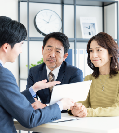 タブレットを見ながら相談する夫婦と担当者